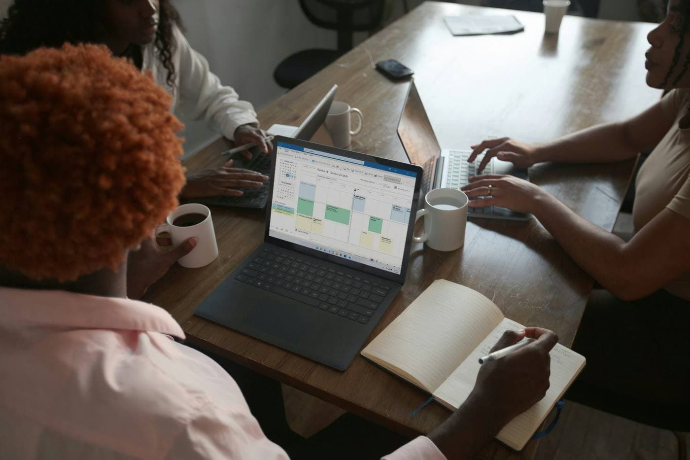 Three colleagues reviewing a schedule on a laptop together
