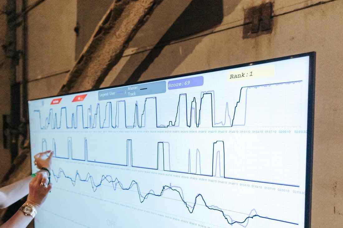 Person pointing at a multi-line chart on a large screen